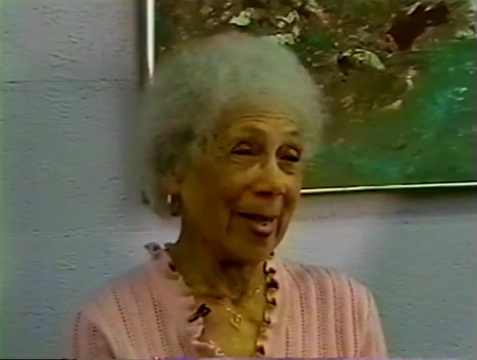 A woman speaks in a still from a video