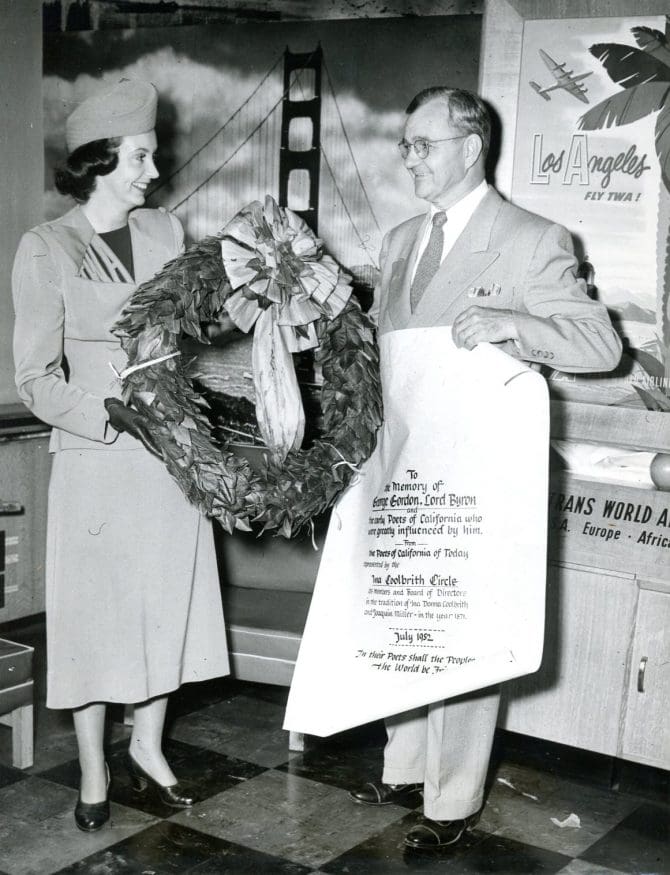 T.W.A hostess Joan Ellis admires the Ina Coolbrith Circle's laurel wreath in honor of Lord Byron. Mr. C. Jones Tyler flew the wreath to Britain, to be placed on Byron's grave, in July 1952.