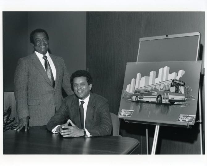 Curtis E. Green and Gregory Lawson standing next to MUNI bus concept drawing