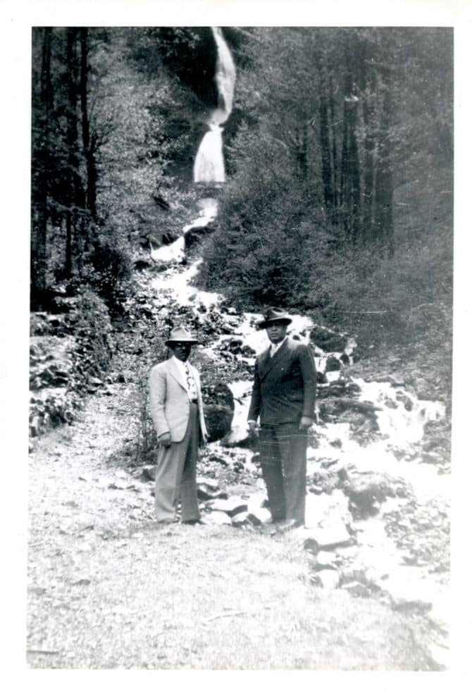 George Vaughns (left) standing with an unidentified man in front of a waterfall, circa 1950s