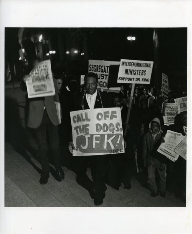 Earl Walter wearing “Call off the dogs, JFK! CORE” protest sign