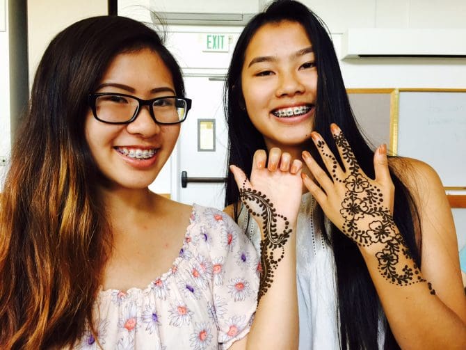Two teens holding up hands showing off henna they received at a library program. 

tags:
teens, henna, do, attend, program, event