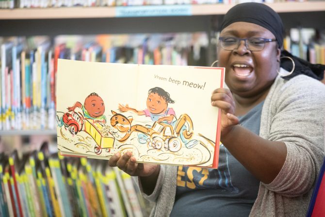 Black librarian reads a children's book featuring Black kids for storytime