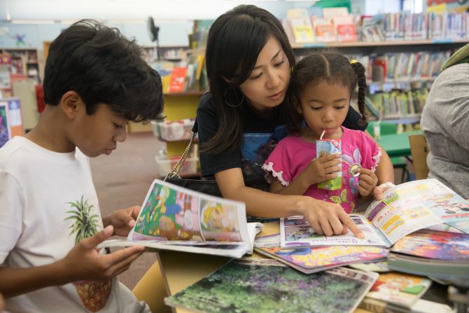 two children are reading books with a caregiver who is pointing to one of the books.
tags:
early literacy, comic books, graphic novels