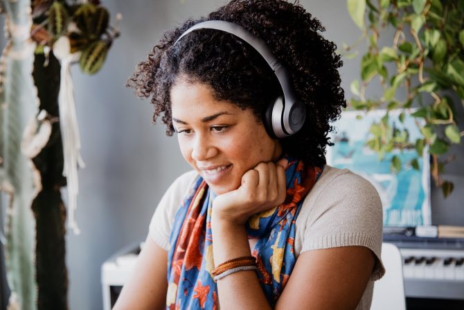 smiling person is wearing wireless headphones while sitting at a desk