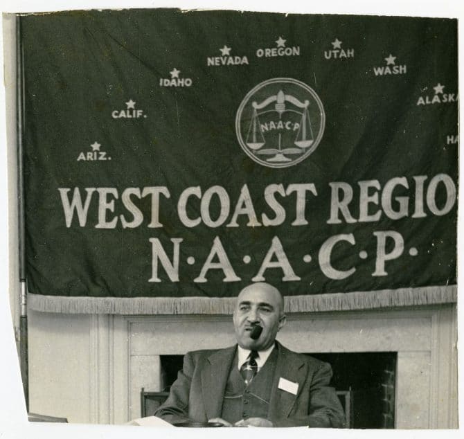 Historic image of C.L. Dellums smoking pipe, West Coast Region N.A.A.C.P. banner