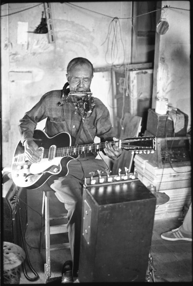 Blues musician Jesse Fuller playing the fodella in his basement