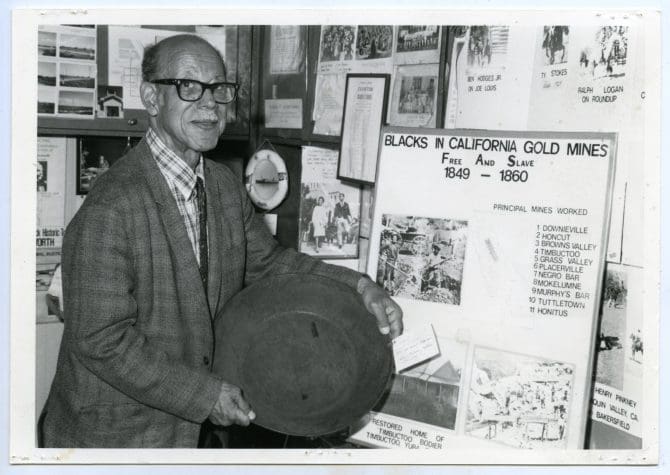 Eugene Lasartemay holding gold at museum exhibit