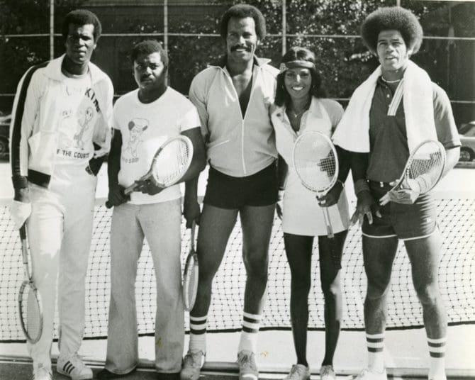Group photograph of Fred Williamson and Pam Grier posing on a tennis court