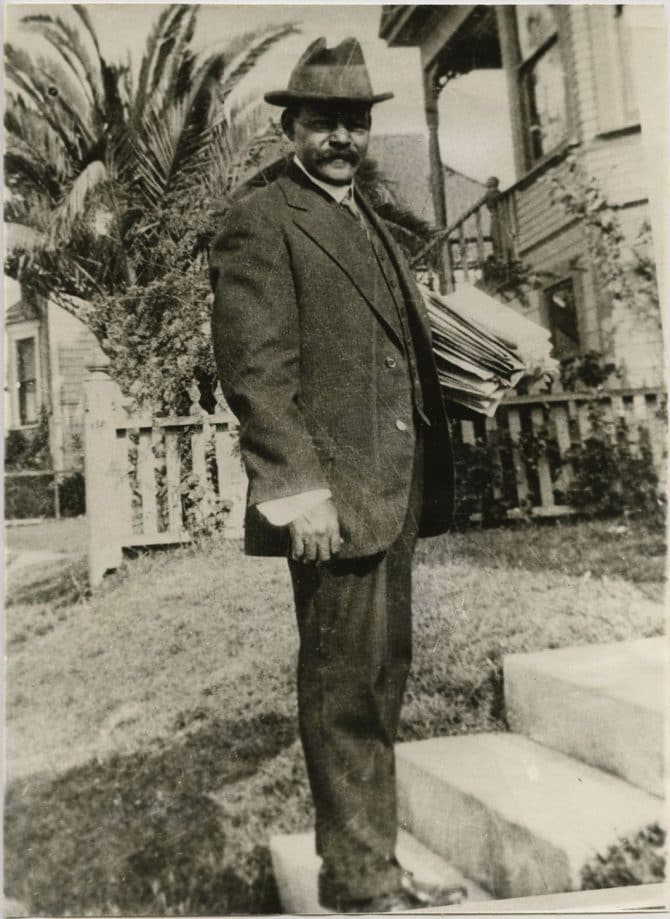 George Watkins standing on walkway holding stack of papers