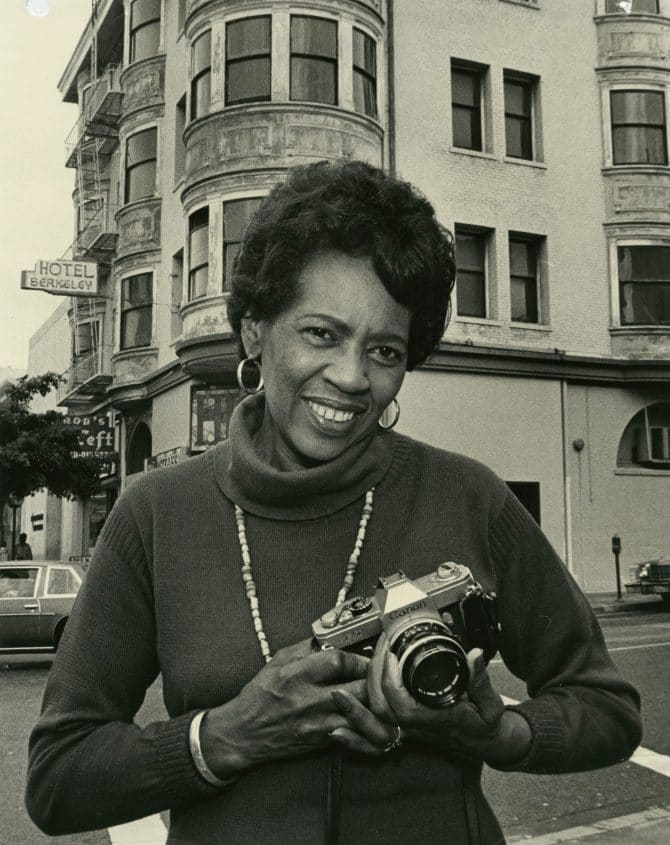Architectural photographer Johnnie Dell Robinson holding camera in front of Hotel Berkeley