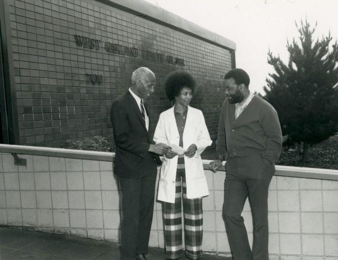 Woman and two men standing outside the West Oakland Health Center circa 1970s