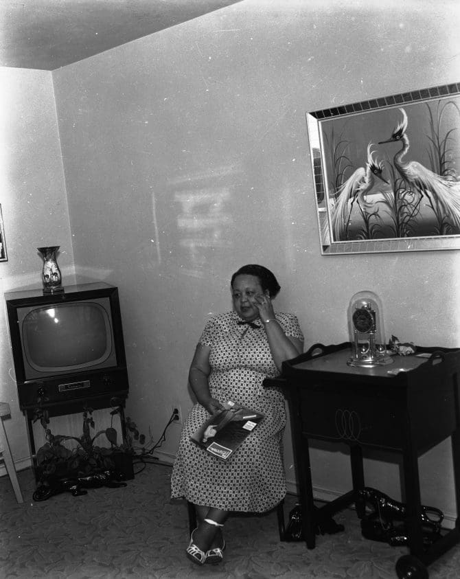Woman seated in living room next to television set