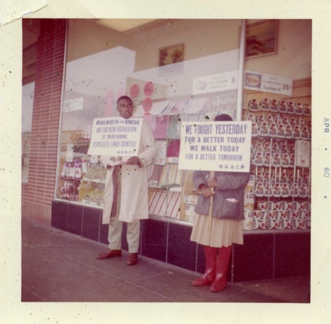 Man and woman holding NAACP picket signs in front of shop window, Squaw Valley Winter Olympics