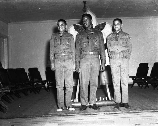 Three boy scouts standing on stage undated