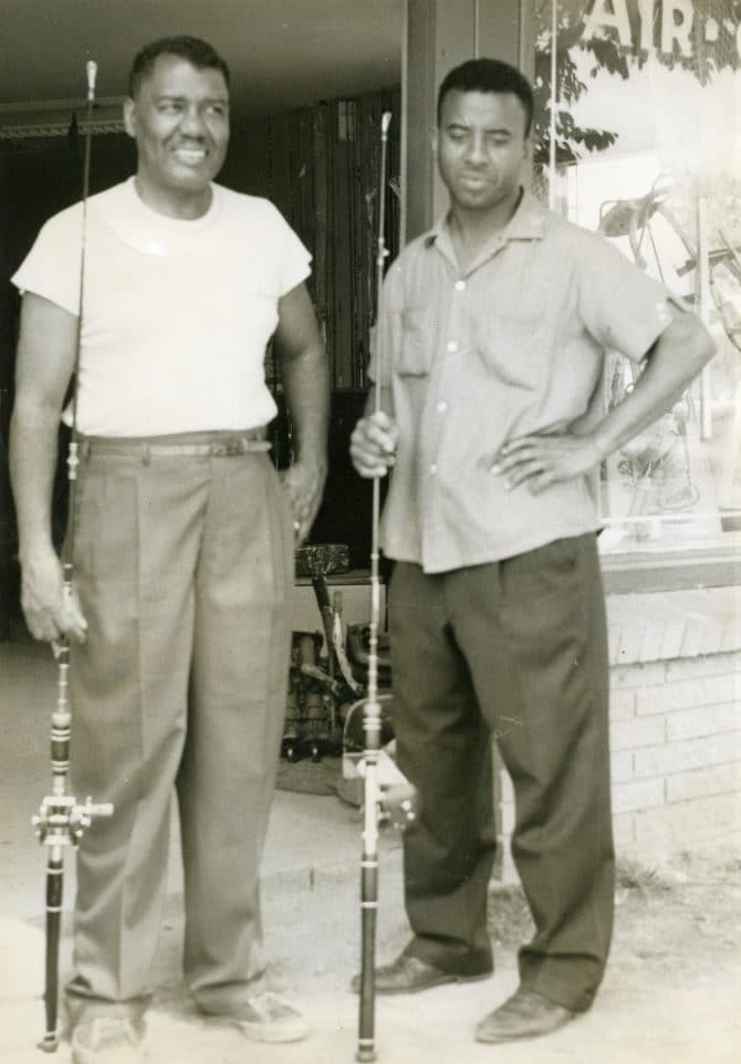 Two men standing with fishing poles, undated
