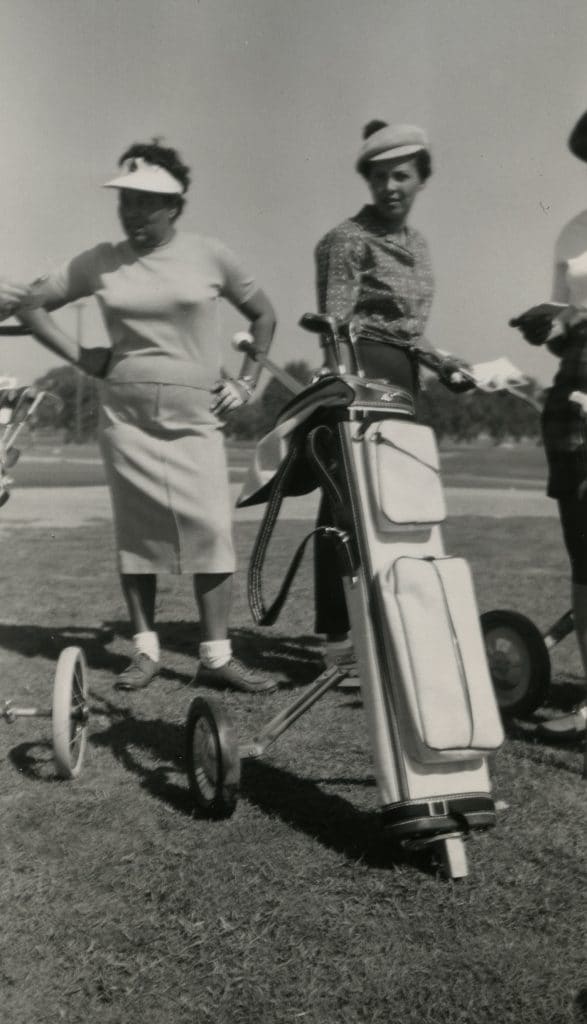 Margaret Nell Wilson and Doralee Petty standing with rolling stand bag, circa 1960s