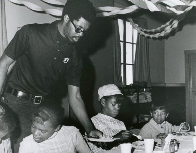 Black Panther Party member serves paper plate of food