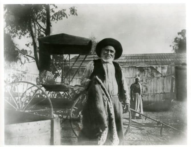 Fernando Reyes standing next to wagon, circa 1880