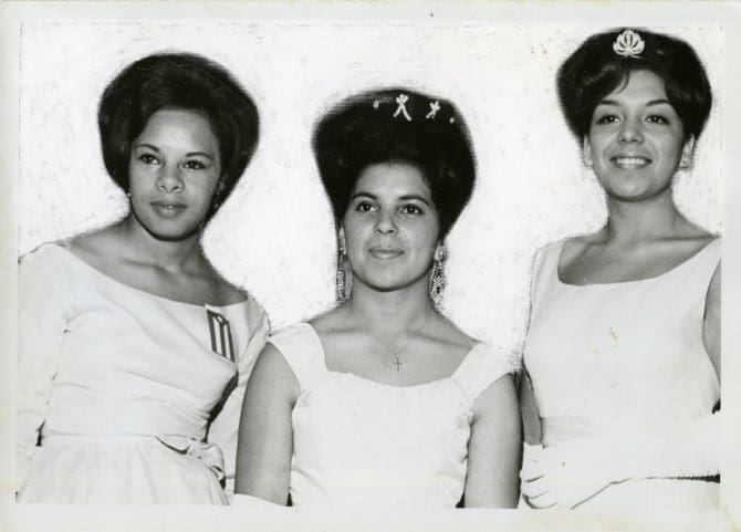 Three women in formal wear, one wearing a Cuban flag, undated