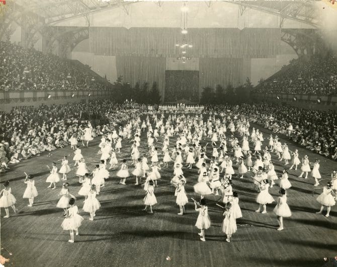 Large group of children filling the floor of a large arena.