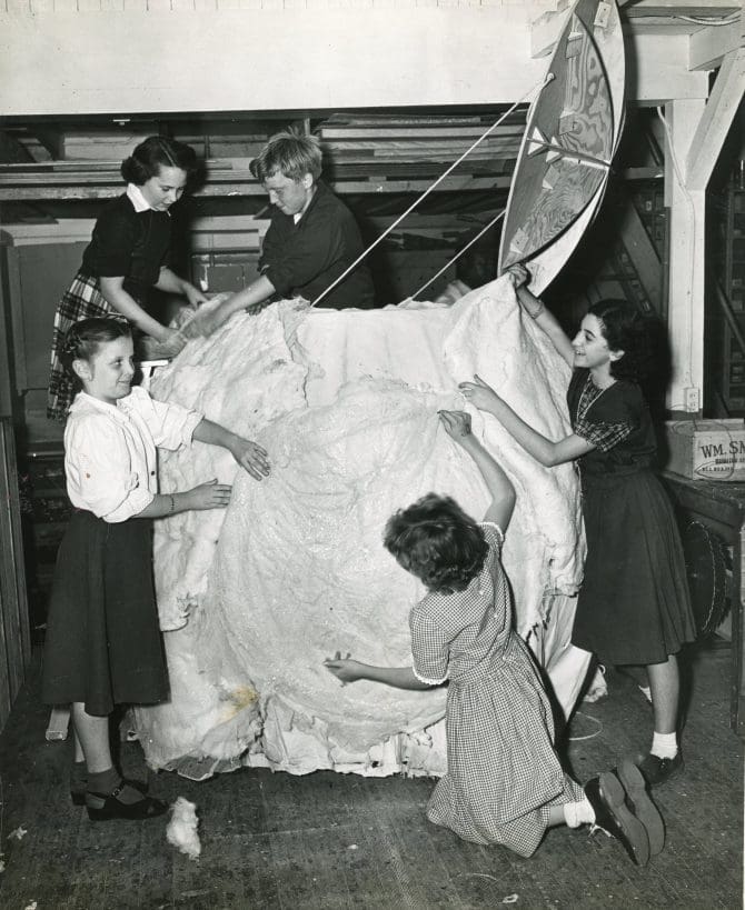 Five children decorating a sphere with a hinged lid to look like a snowball.