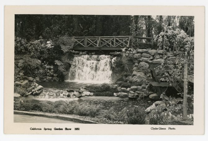 Black and white image of a wooden bridge over a wide waterfall