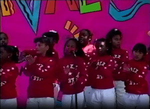 Image from a video of the Festival at the Lake's 1992 Young Artists Stage, showing children wearing red sweatshirts printed with the words Jazz All-Stars.