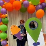 Two CPL employees pose with cardboard cut outs in front of a balloon arch
