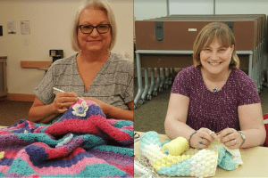 Two female volunteers hosting a knitting/crochet program.