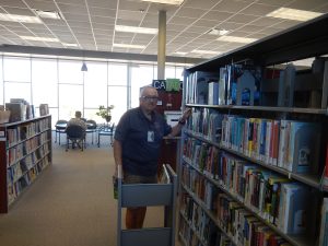 Male volunteer at the Foothills Library shelving and facing items.