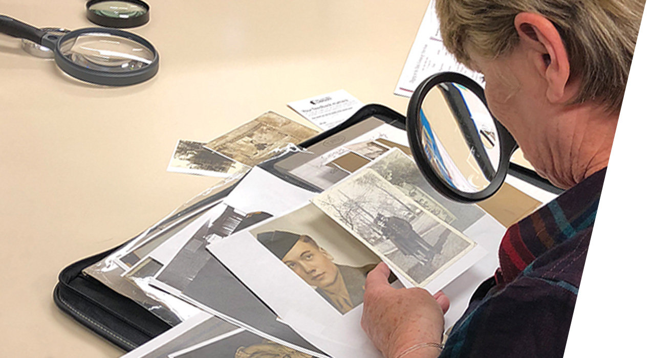 A woman uses a magnifying glass on old photos