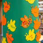 A post covered in green paper and cutout yellow and orange bees.