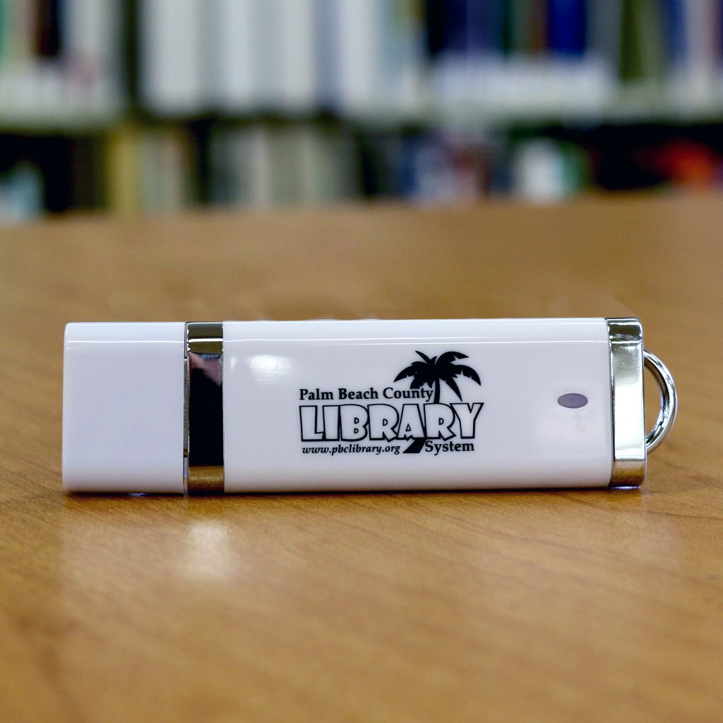 White USB flash drive with Palm Beach County Library System logo