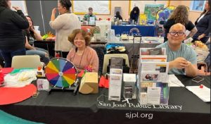 library staff smiling as they sit behind their resource table