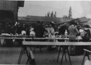 Outdoor scene of long tables set up outside with food and possibly other supplies for people in need of assistance following the earthquake.