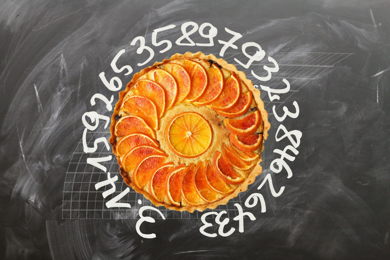 Hình ảnh một tấm bảng đen có các số 3.1415926535897932384626433 được viết xung quanh hình ảnh một chiếc bánh màu cam.
