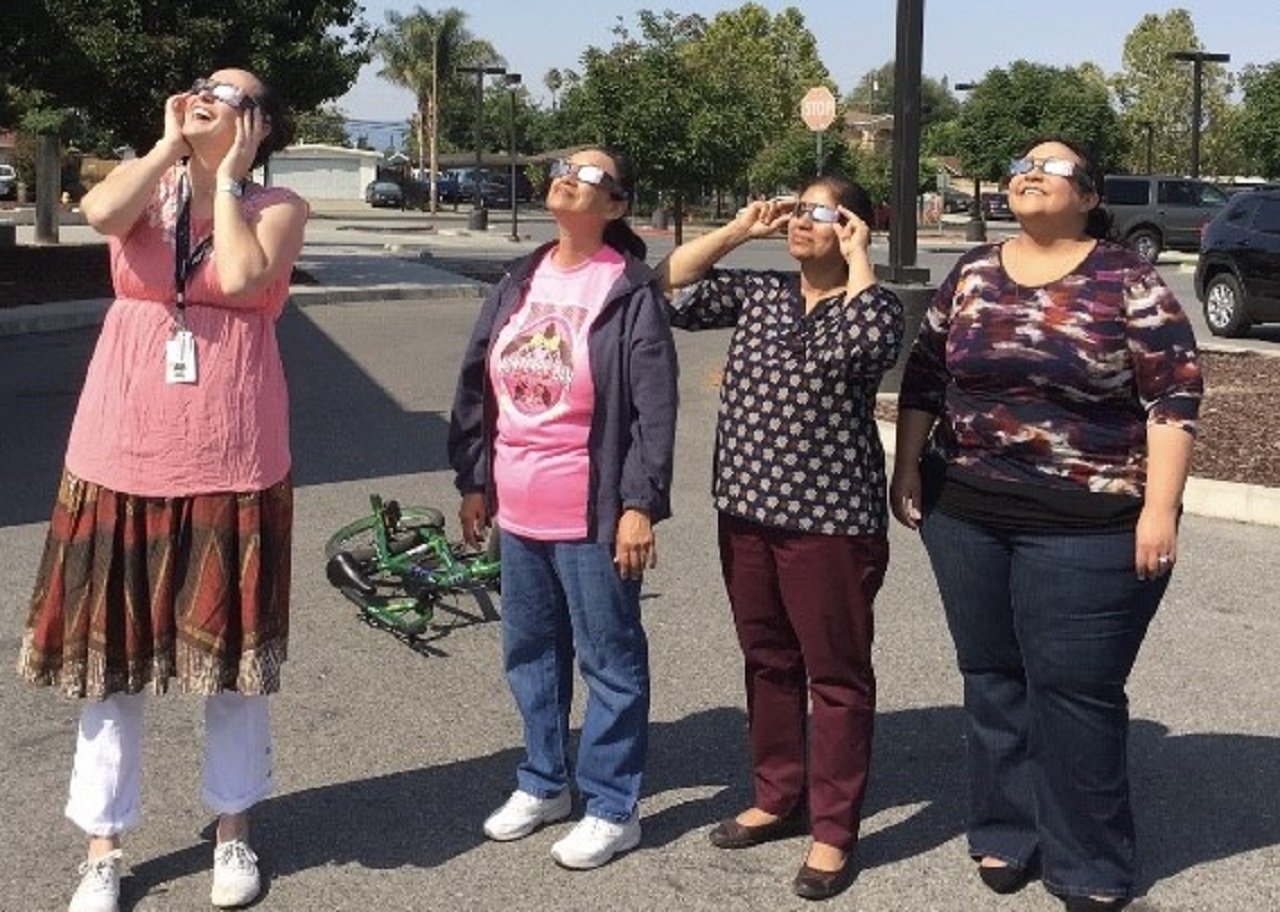 Four women watching an eclipse at the library.