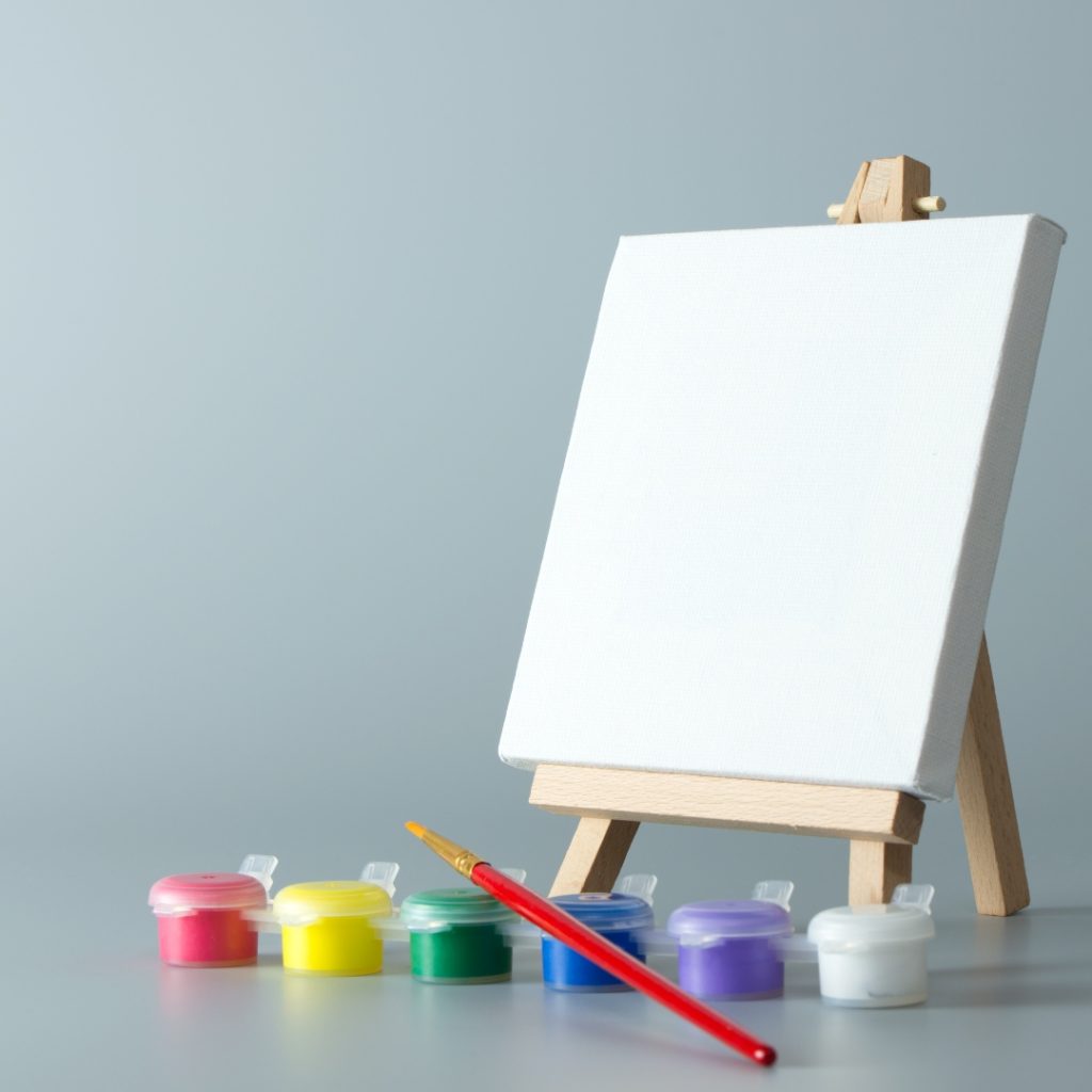 Easel with set of paints and paintbrush.