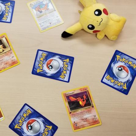 Pokémon trading cards and stuffed animals on spread out on table.