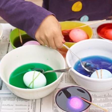 Huevos en tazones de agua con tinte de varios colores.