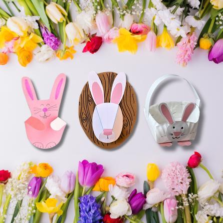 Three bunny crafts rest amid a white surface with colorful spring flowers.