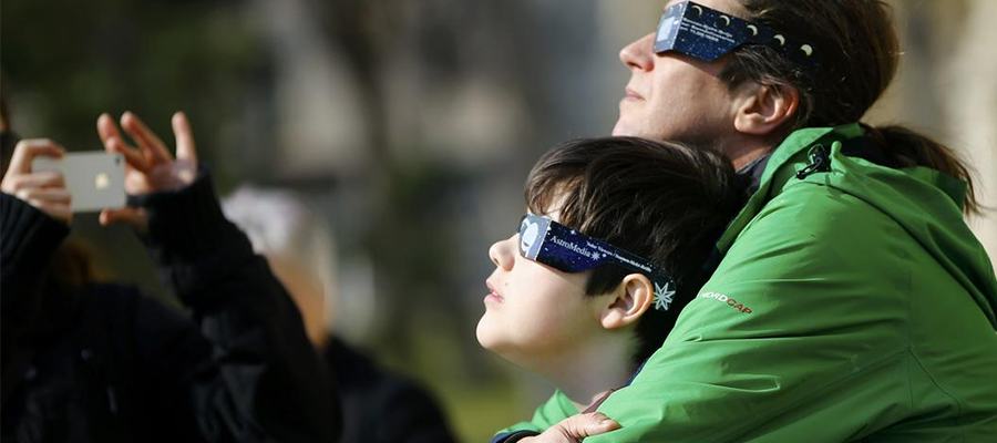 People use protective glasses to observe a partial solar eclipse.