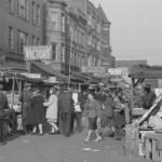 people, carts, and goods in a crowded street scene