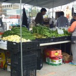 shoppers examining piles of vegetables on tables