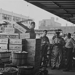 Workers standing next to boxes of produce