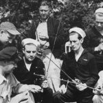 Seven veterans, some in uniform, holding fishing poles
