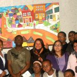 teens standing in front of a colorful painting of houses
