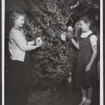 two girls decorate a Christmas tree