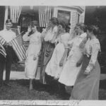 Man holding American flags while 5 women salute